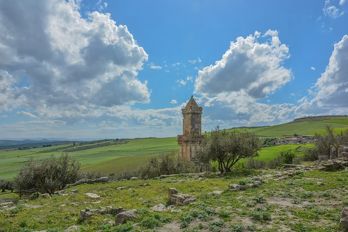 The tall stepped Libyco-Punic mausoleum standing among olive trees and green fields near Dougga